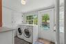 A bright and functional laundry room offers generous built-in storage, full-size washer and dryer space, and direct access to the pool and backyard.