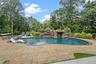 View of pool with a patio, a pool with connected hot tub, and view of wooded area