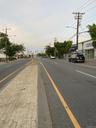 View of asphalt street featuring street lighting, sidewalks, and curbs