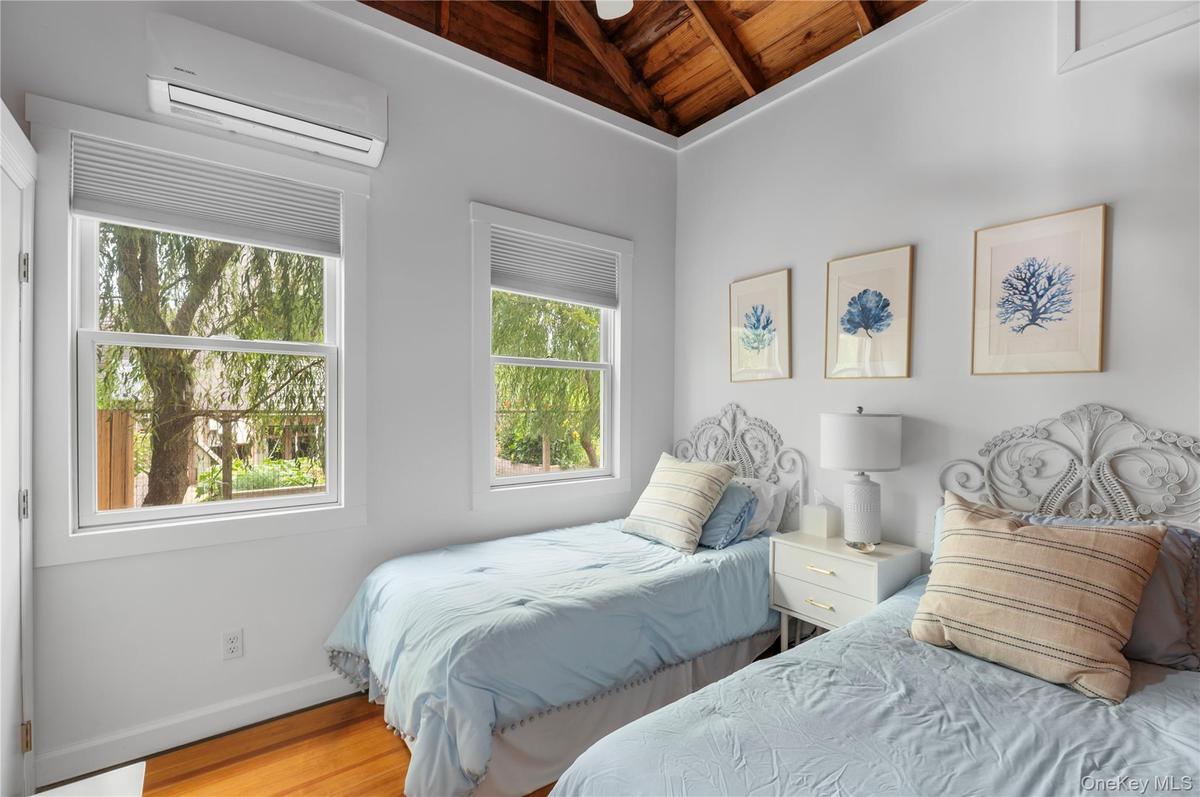 Bedroom featuring wooden ceiling, a wall mounted air conditioner, wood finished floors, and lofted ceiling