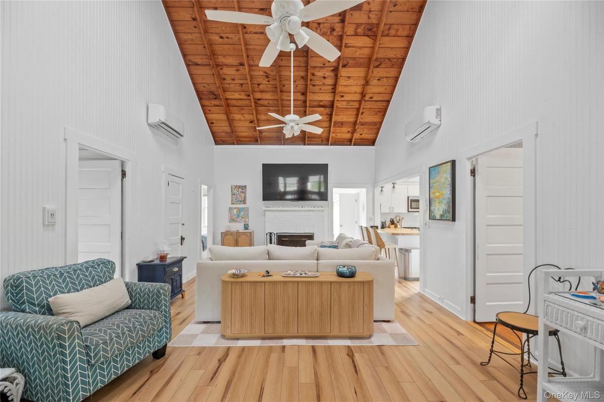 Living room featuring high vaulted ceiling, a fireplace, wood finished floors, and wood ceiling