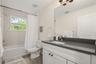 Bright guest bathroom featuring a single vanity, tub/shower combination, and a functional layout.