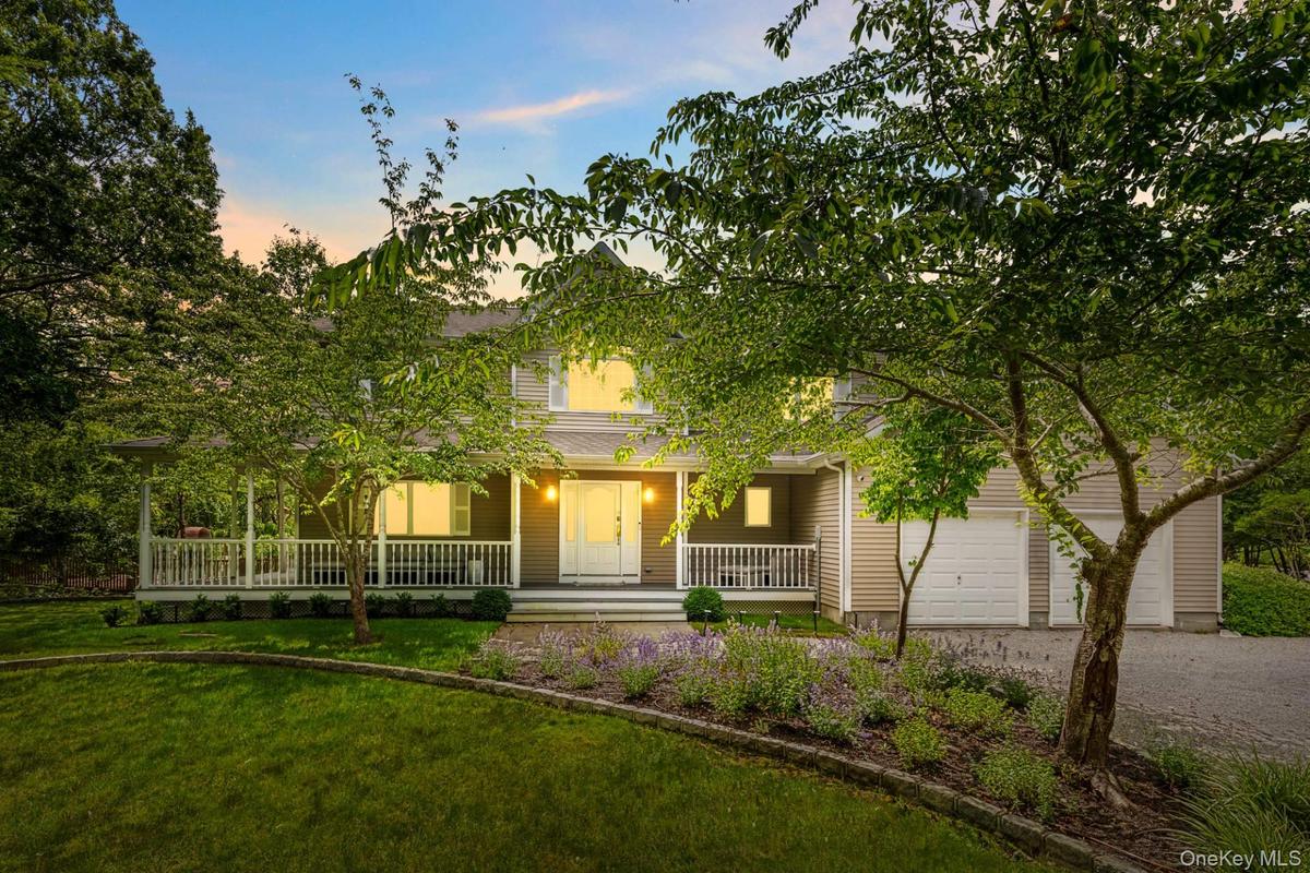 Obstructed view of property featuring a porch, driveway, a garage, and a yard