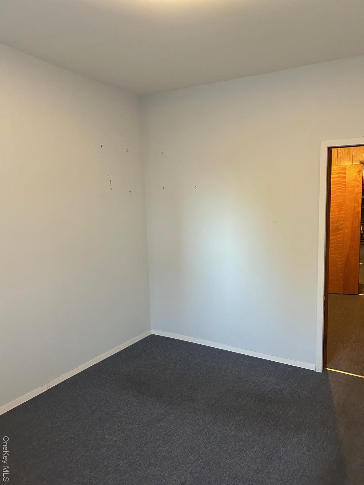 Unfurnished room with dark colored carpet and baseboards