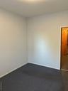 Unfurnished room with dark colored carpet and baseboards