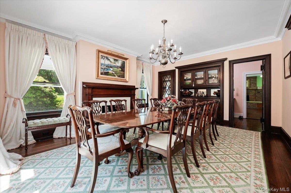 Formal and fabulous with wood burning fireplace, original built-in breakfront and glassware closet, oversized windows, wood floors, moldings and swing