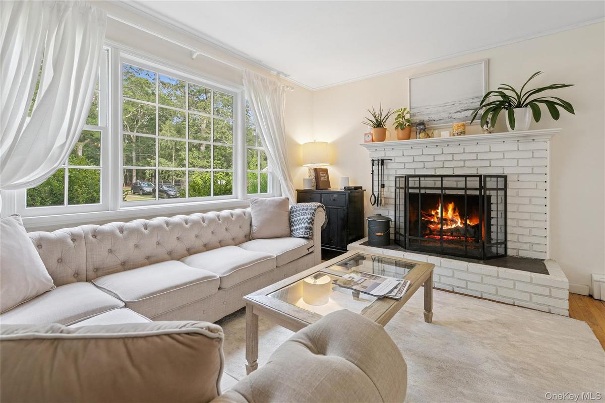 Living area with a fireplace, ornamental molding, and wood finished floors