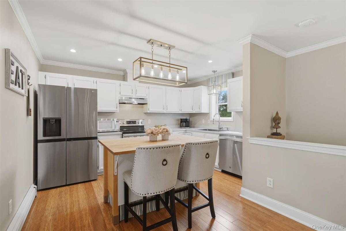 Kitchen featuring white cabinetry, stainless steel appliances, a wood-finish island, and recessed lighting