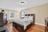Bedroom with light wood finished floors, radiator heating unit, and lofted ceiling