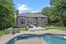 Back of property with an outdoor fire pit, a patio, a chimney, an outdoor pool, and roof with shingles