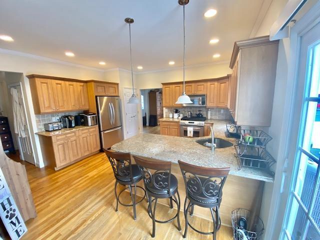 Kitchen featuring backsplash, kitchen peninsula, pendant lighting, and appliances with stainless steel finishes