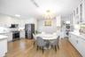 Dining room with stacked washer / dryer, light wood-style floors, ornamental molding, and a chandelier