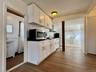 5 - Kitchen with stainless steel microwave, dark wood-style flooring, white cabinetry, and dark countertops