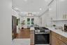 Modern kitchen featuring white shaker upper cabinetry and natural wood lower cabinetry with gold-tone hardware