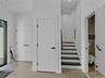 Stairs to second floor with coat closet and entrance to half bathroom