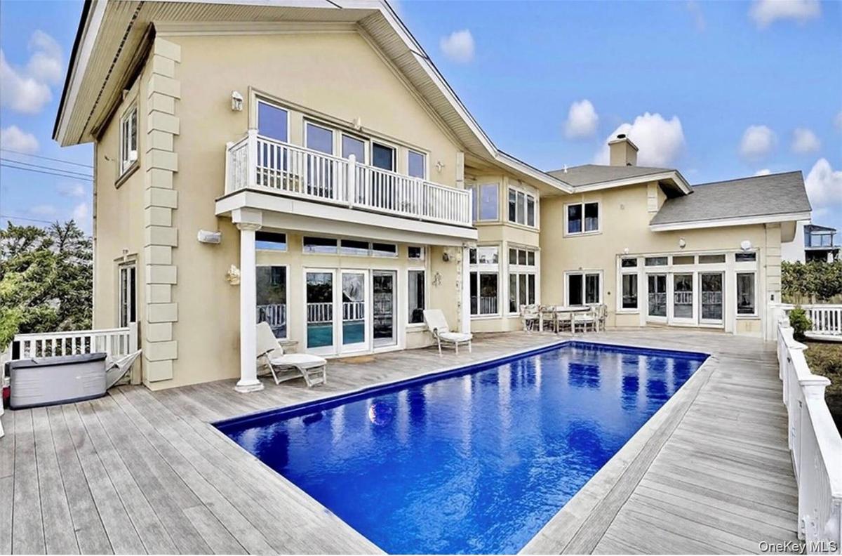 Back of property featuring french doors, stucco siding, a balcony, and a chimney