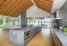 Kitchen featuring wall chimney range hood, light wood-style floors, a water view, modern cabinets, and open floor plan