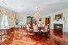 Open-concept room featuring intricate parquet wood-finish flooring, a white-mantled fireplace, and a crystal chandelier