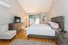 Bedroom featuring a wall mounted air conditioner, access to outside, vaulted ceiling, and wood finished floors