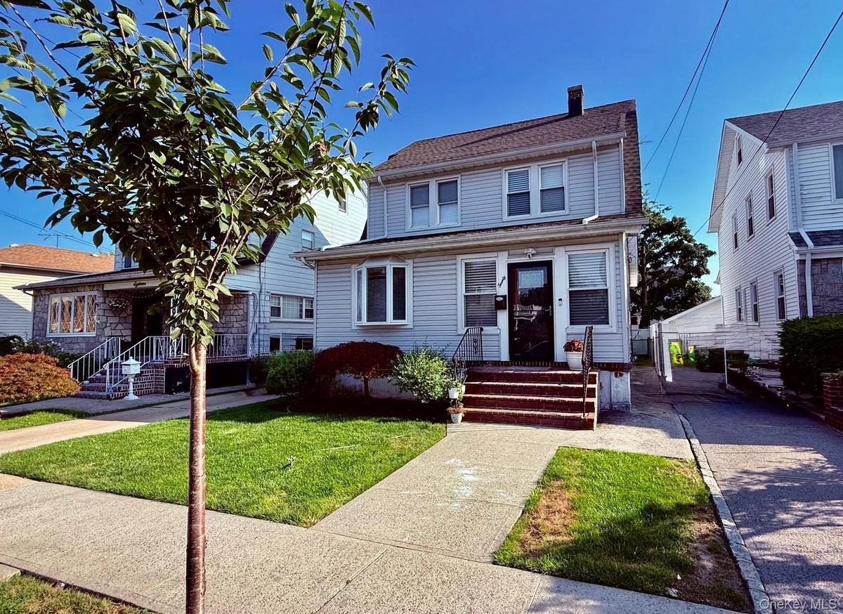 Two-story residence with light-colored siding, dark shingle roof, and a paved driveway