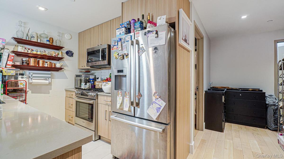 Kitchen featuring stainless steel appliances, light brown cabinets, recessed lighting, decorative backsplash, and open shelves