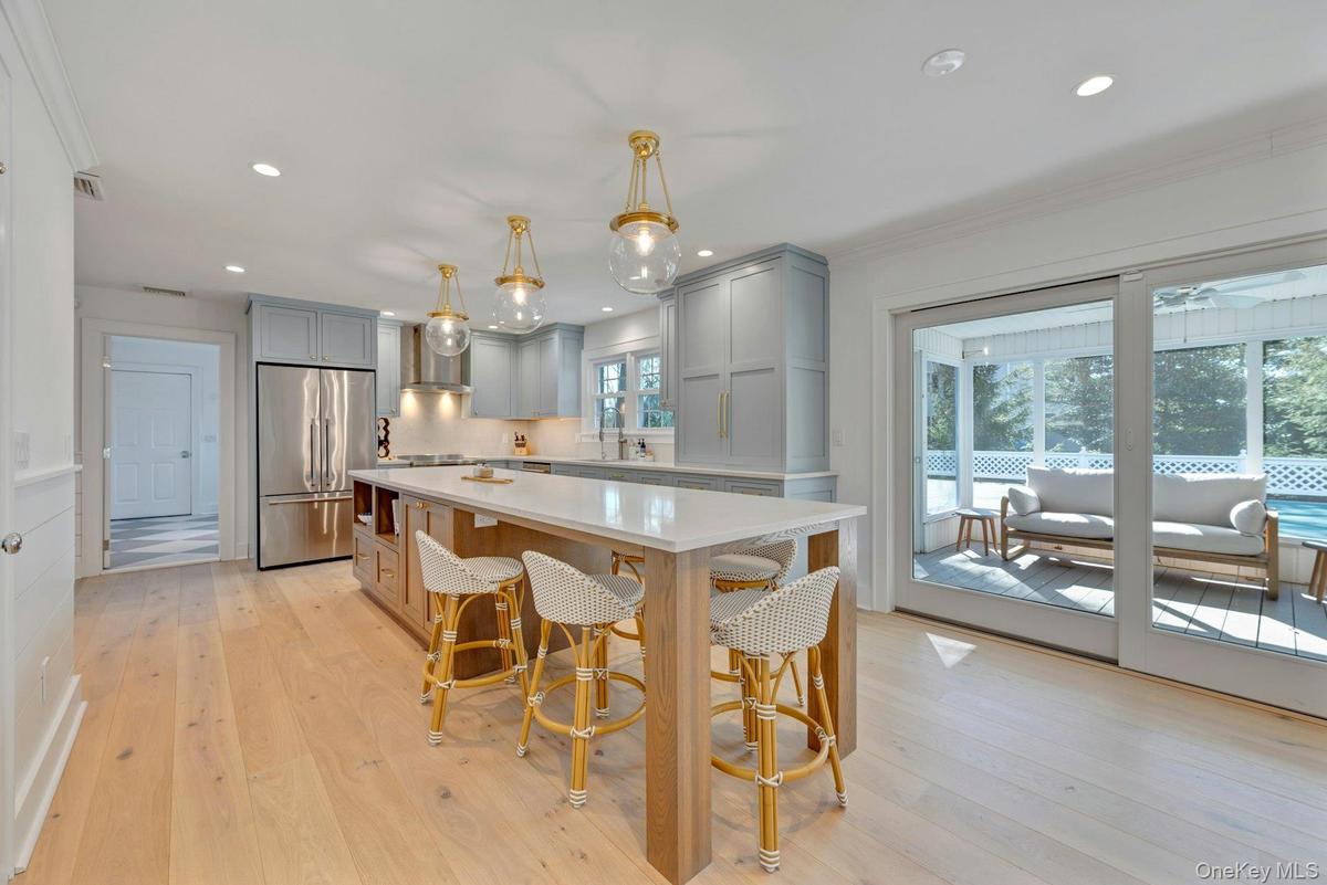 Kitchen featuring hanging light fixtures, high quality fridge, gray cabinets, light wood finished floors, and recessed lighting