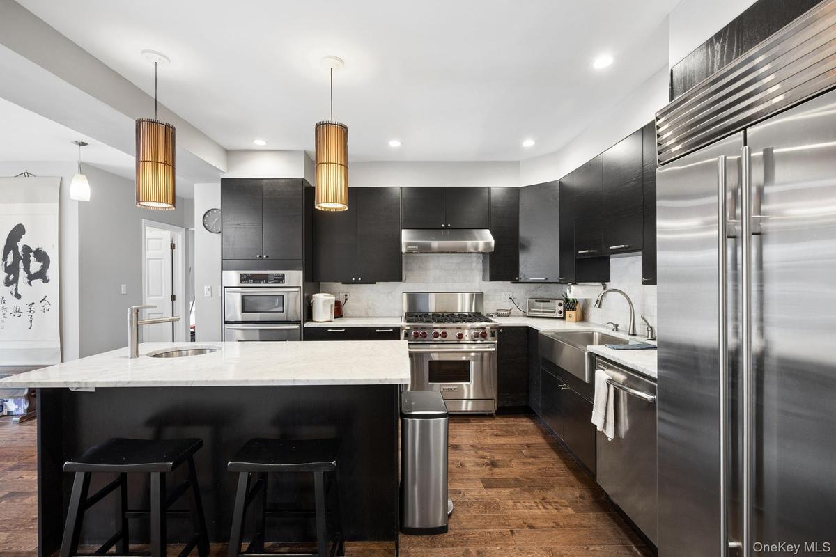 Gourmet eat-in kitchen featuring custom cabinetry, quartz countertops, a spacious center island with seating, and premium stainless steel appliances. 