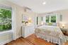 Bedroom with a wall mounted air conditioner, multiple windows, light wood-type flooring, ornamental molding, and recessed lighting