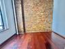 Unfurnished room featuring wood finished floors and brick wall