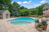 Expansive outdoor living area featuring a large swimming pool with an integrated spa