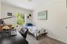Room featuring neutral-toned walls, carpet flooring, and a large window with white blinds