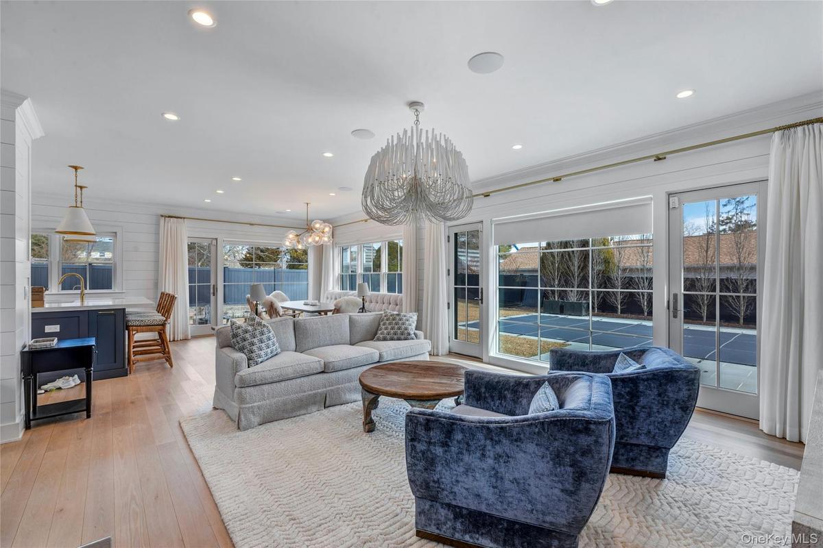 Bright, expansive living room in a New Suffolk retreat featuring floor-to-ceiling windows and abundant natural light