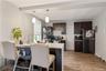 Modern kitchen featuring dark wood cabinetry, a central island with an undermount sink, white countertops, and wood-finish flooring