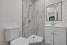 Modern bathroom featuring a corner shower with abstract tilework, a white shower pan, and chrome fixtures