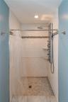 Shower featuring white subway tile walls, a mosaic tile accent band, a multi-function shower panel with an overhead rainfall shower, and a white mosai
