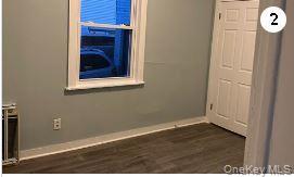 Unfurnished room featuring baseboards and dark wood-type flooring