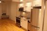Kitchen featuring appliances with stainless steel finishes, radiator, tasteful backsplash, light stone counters, and light wood-style flooring