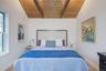 Bedroom featuring vaulted ceiling, wood walls, light wood-style floors, and multiple windows