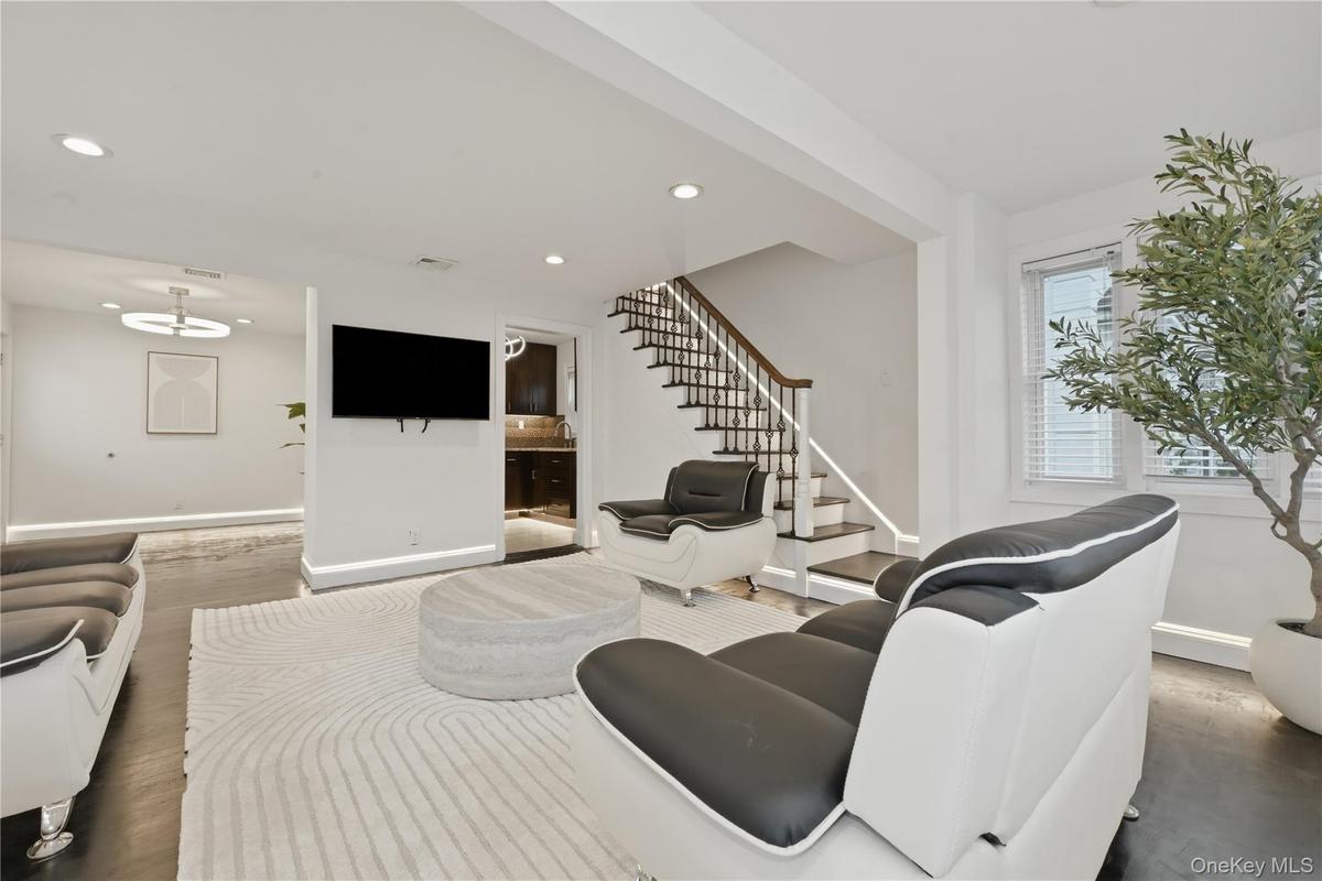 Living area featuring dark wood-finish flooring and a contemporary staircase with white risers and dark wood handrails