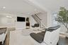 Living area featuring dark wood-finish flooring and a contemporary staircase with white risers and dark wood handrails