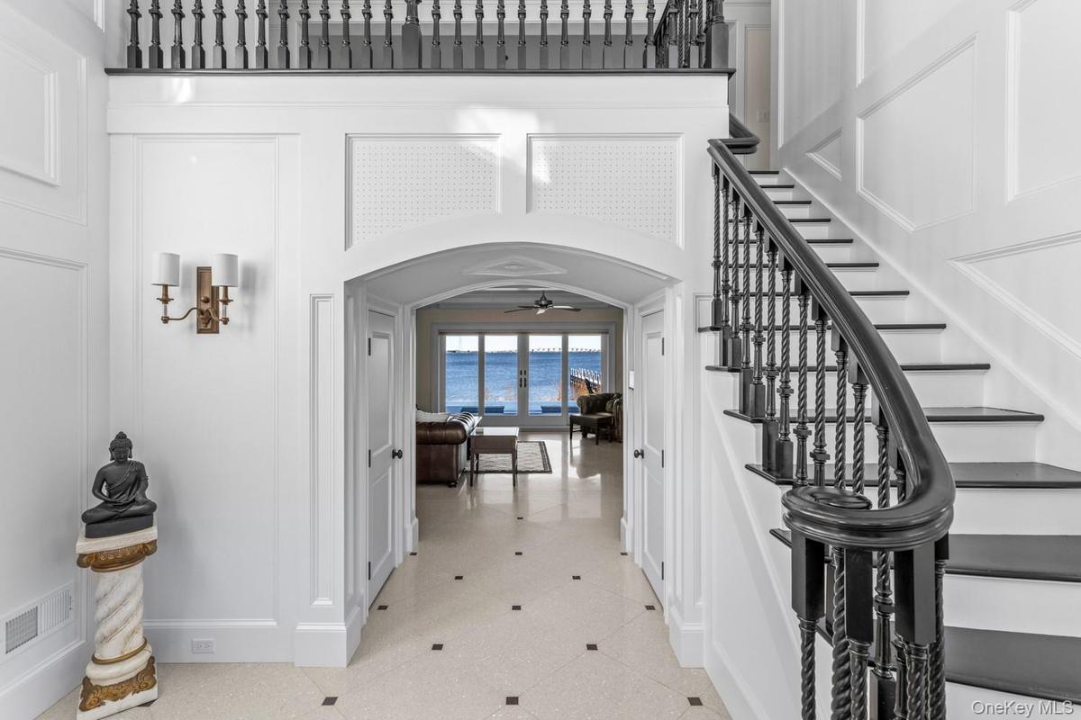Foyer entrance featuring arched walkways, a ceiling fan, stairway, and a decorative wall