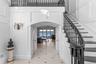 Foyer entrance featuring arched walkways, a ceiling fan, stairway, and a decorative wall