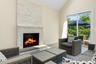 Living area featuring vaulted ceiling, a brick fireplace, and wood finished floors