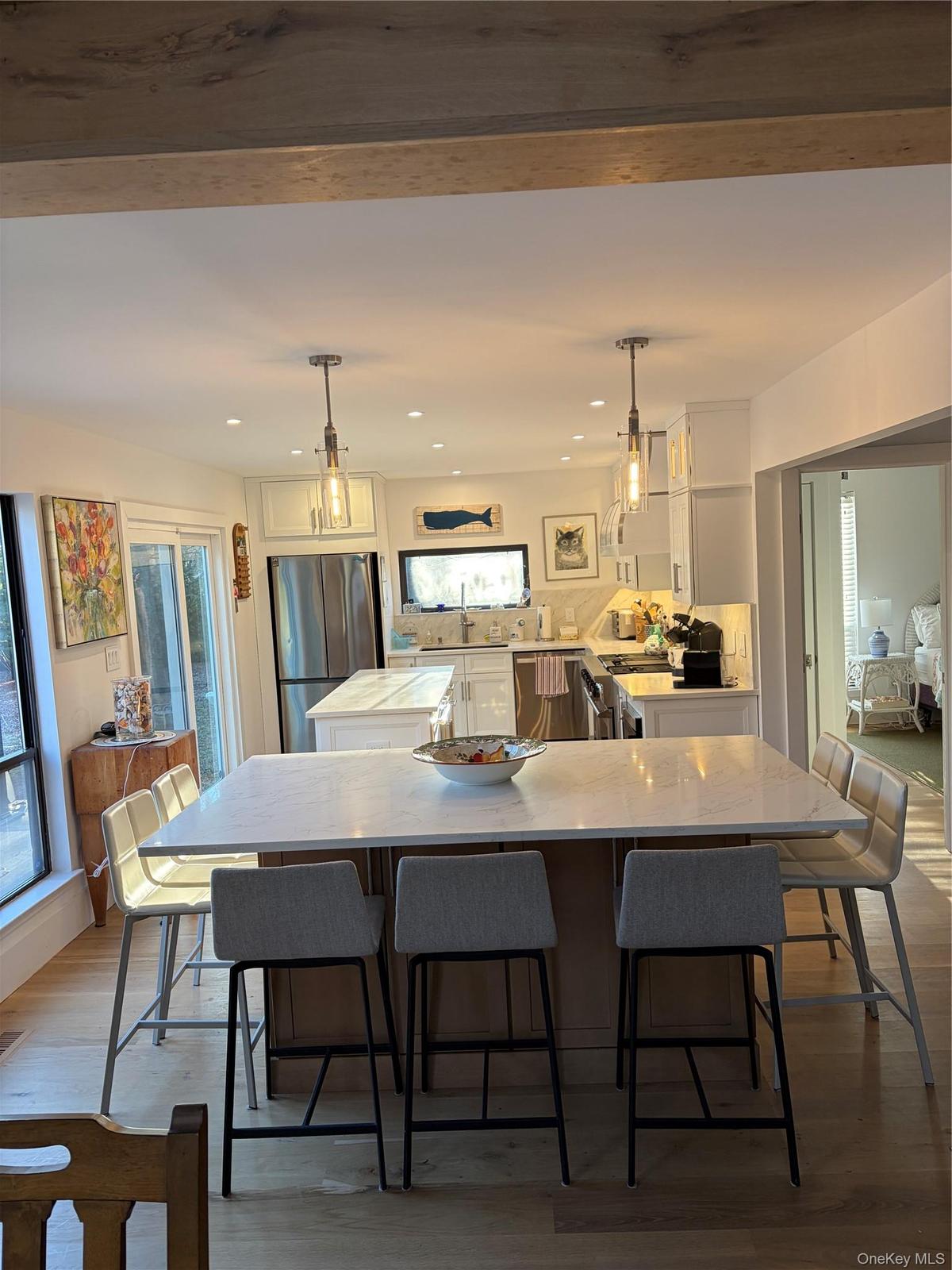 Kitchen with a center island, white cabinets, dark wood-type flooring, and hanging light fixtures