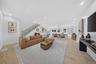 Open-concept interior featuring wood-finish flooring, recessed lighting, a staircase with decorative balusters, and multiple windows