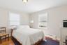 Bedroom with baseboard heating, wood finished floors, and crown molding