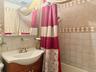 Bathroom featuring a tiled shower surround with decorative accent banding, a wood-finish vanity with an integrated sink, a wall-mounted mirror, and a 