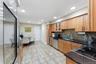 Kitchen featuring wood cabinetry, dark countertops, a mosaic tile backsplash, stainless steel appliances, and tile flooring