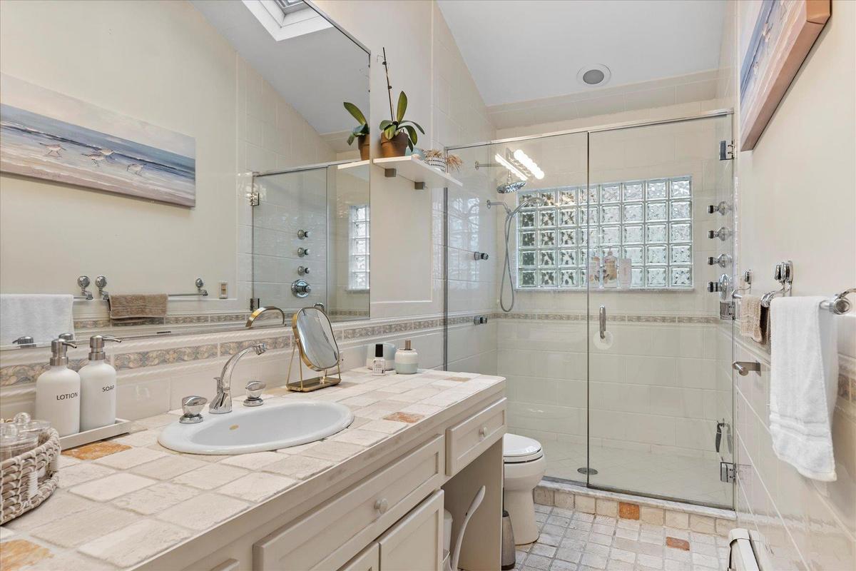 Full bathroom featuring toilet, tile walls, vanity, and a stall shower