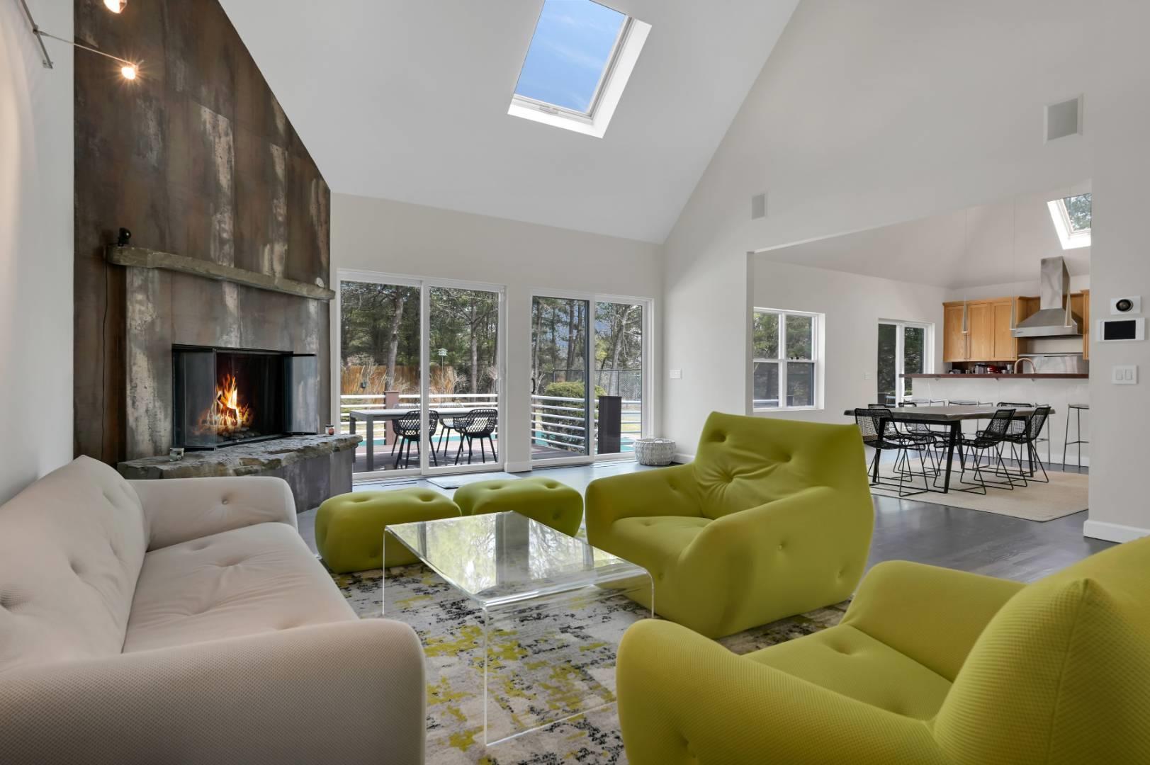 Living area featuring a skylight, visible vents, a premium fireplace, wood finished floors, and high vaulted ceiling